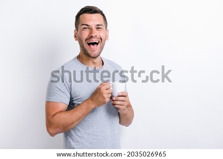 Waist up portrait view of the happy caucasian man standing and rejoicing with the cup of coffee. Morning beverages concept. Stock photo