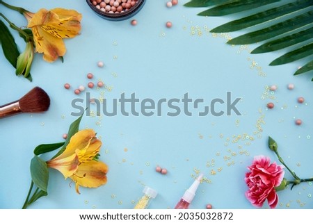 Cosmetic products, accessories, brushes for makeup and powder. Flowers decorations. Beauty concept. Top view, copy space blue background. High quality photo