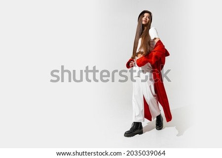 Fashion studio photo of stylish european brunette woman in red coat and black hat posing on white background.  Trendy winter accsesorises. Full lenght. 