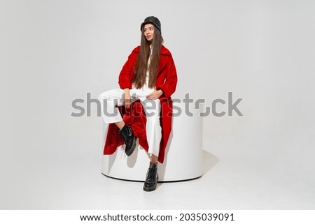 Fashion studio photo of stylish european brunette woman in red coat and black hat posing on white background.  Trendy winter accsesorises.