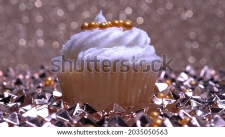 Cupcake macro shallow depth of field and decoration with sugar sprinkles. Cup cake with white vanilla cream on gold background. Process of making delicious desserts muffin for delivery or sale. 
