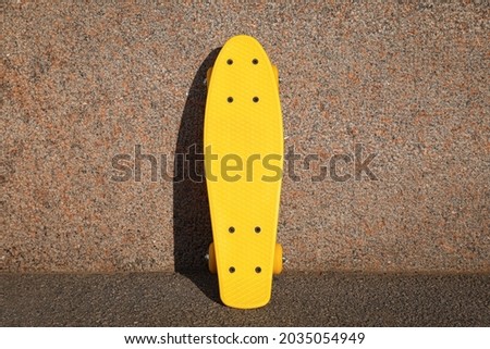 Stylish yellow skate board near wall outdoors
