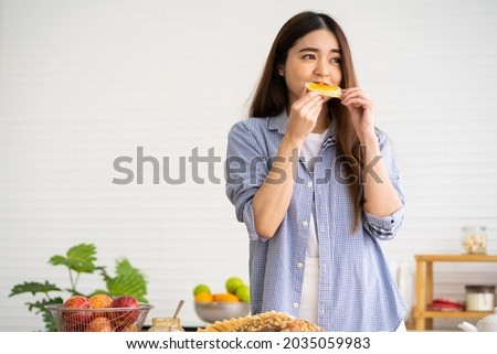Young Asian women wake up in the morning and prepare bread for breakfast in the kitchen with different type of salad vegetable and healthy food. Good nutrition eating human body condition.