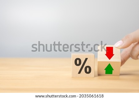 Hand flip wood cube change arrow down to up. Changes in interest rates. Hand is turning a dice and changes the direction of an arrow symbolizing that the interest rates are going down