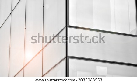 Modern architectural details. Modern glass facade with a geometric pattern. Contemporary corporate business architecture. Red sun on horizon. Black and white toned image.