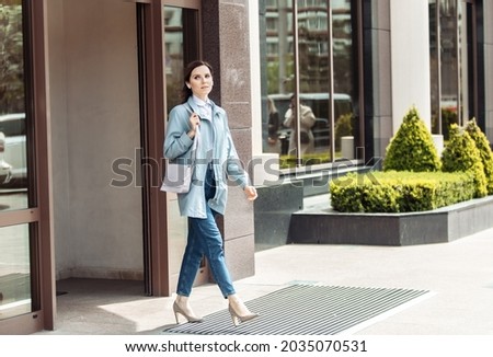 Cute woman comes out of the building. Lifestyle