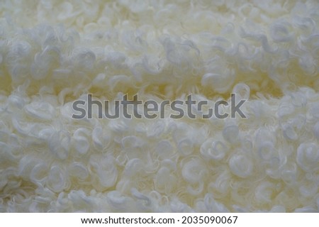 Faux fur of white pale yellow color. Imitation of karakul lamb skin. known as fleecy fabric, which resembles animal fur in appearance and warmth.