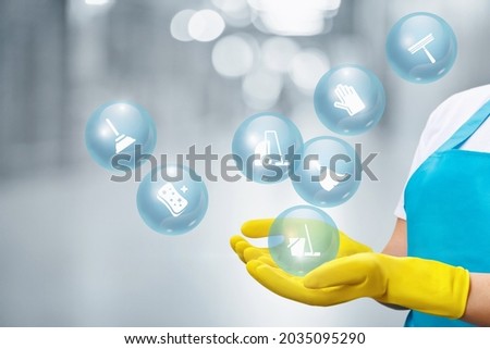 Cleaning lady shows service icons on blurred background. Royalty-Free Stock Photo #2035095290