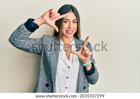 Young hispanic woman wearing business clothes smiling making frame with hands and fingers with happy face. creativity and photography concept. 