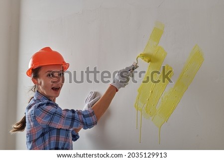 repairwoman beautifully painted wall in yellow with a roller