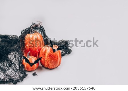 Minimal Halloween scary and funny concept. Decorative orange pumpkins with bat shape mustache on light gray background with copy space. Halloween decorations or party invitation, selective focus