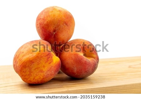 Three (3) fresh, ripe peaches on a wooden board isolated on white