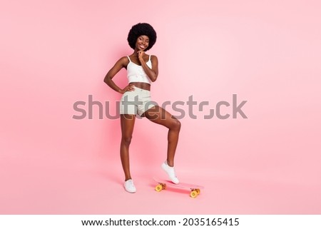 Full body photo of cool young curly hairdo lady ride skate wear white top shorts isolated on pastel pink color background