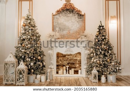 Two decorated Christmas trees on the sides of the hall and a fireplace in the center. Christmas and New Years with rich traditional home decor. Candles gifts in boxes and Christmas toys for christmas