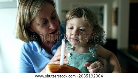 Grandmother holding baby infant celebrating one year old birthday, cake with candle