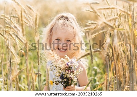 Little cute blonde girl with a bouquet of wildflowers in nature in the summer