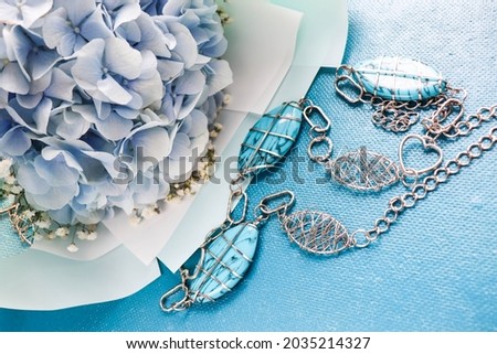 romantic composition. bouquet of blue hydrangea and jewelry. necklace of blue stones on a chain 