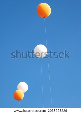 Large white and orange balloons fly in the sky