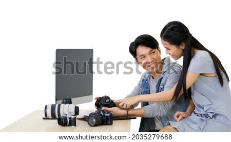 Asian photographer and model looking at pictures taken on the camera screen. The young model is very satisfied with her photo. The atmosphere in the photo studio.