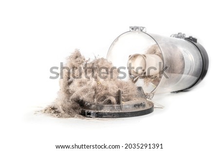 Open cyclonic vacuum canister spilling out dust, debris, pet fur and hair. Perspective view of vac storage tank fallen over or emptying dirty content on the floor. Selective focus. Isolated on white. Royalty-Free Stock Photo #2035291391