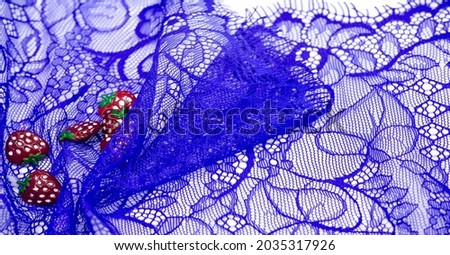 Lace fabric in blue. Plastic strawberries. Decorative strawberries can be sewn onto fabric. Bright decoration. Texture Background Pattern