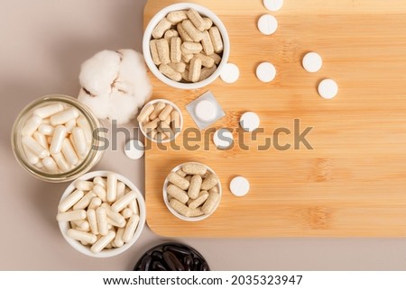 Nutritional supplement and vitamins to support human health and immune system on brown background. There are such organic vitamins as omega 3, chelated magnesium, zinc, vitamin C, multivitamin complex Royalty-Free Stock Photo #2035323947