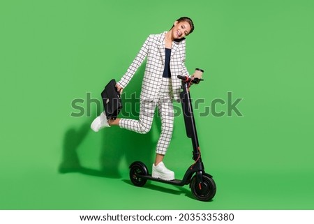 Photo of cute charming young lady wear plaid outfit driving eco transport holding case talking modern device isolated green color background