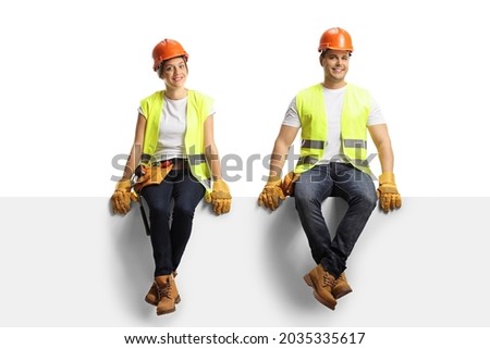 Male and female construction workers sitting on a panel and smiling at camera isolated on white background Royalty-Free Stock Photo #2035335617