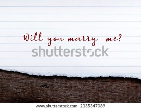 lined note on old wood background with handwritting WILL YOU MARRY ME?  a simple standard marriage proposal when someone pop a question to the one they love