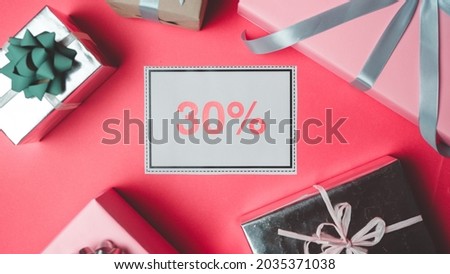 Portrait Photo of a Sign That Says 30% Off In The Middle, Surrounded With Beautiful Gift Boxes With Cute Ribbons on a Red Colored Background.
