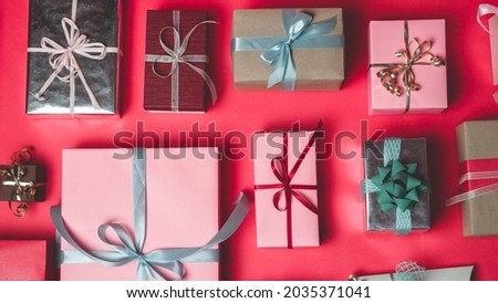 Beautiful Photo of Different Colored Gift Boxes, Pink, Silver and Brown, Layed Out on a Red Colored Background. Symmetrical Placement of Various Presents.