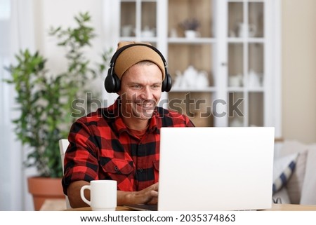Young handsome man with headphones working at home on laptop