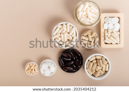 Top view composition of nutritional supplements on light background. Multivitamin complex , natural, organic and vegan vitamins in a beautiful composition. Supplements for support human health, immune Royalty-Free Stock Photo #2035404212