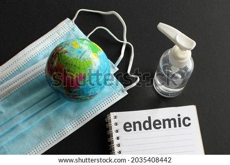 Medical and healthcare concept. Facemask, hand sanitizer, earth globe and notebook with text ENDEMIC Royalty-Free Stock Photo #2035408442