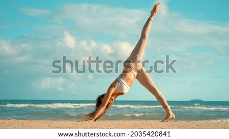 Caucasian woman practice yoga on the beach. Young woman practice balance asanas on Summer yoga session on a beach. Happy young woman practicing yoga on the beach at sunset.