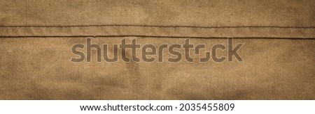 Wide panoramic surface texture of army rough khaki fabric with seam and dark vignette. Template for design and site header Royalty-Free Stock Photo #2035455809