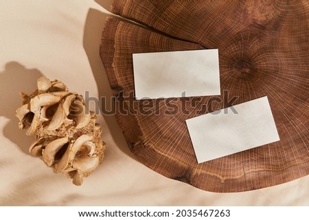 Flat lay of creative composition with mock up visit cards, wood, natural materials and accessories. Neutral colors, top view, template.