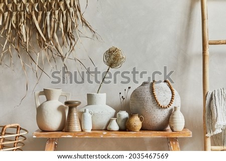 Stylish composition of living room interior with copy space, bench in retro style, clay vases and crockery. Rustic inspiration. Summer vibes. Beige wall. Template.