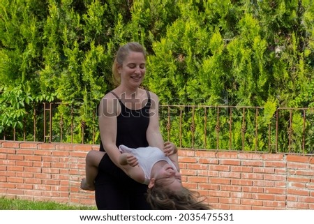 The young woman is dancing in the garden with her little daughter in her arms. Selective Focus. motion picture.