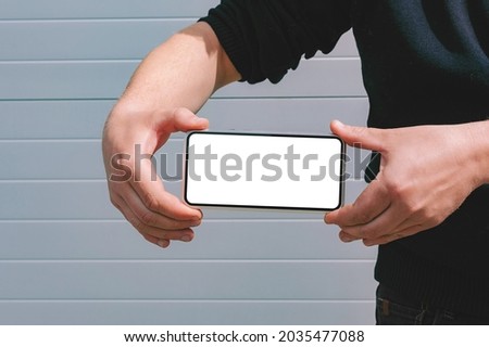 Mock up of a smartphone in the hands of a man. against the background of a gray wall