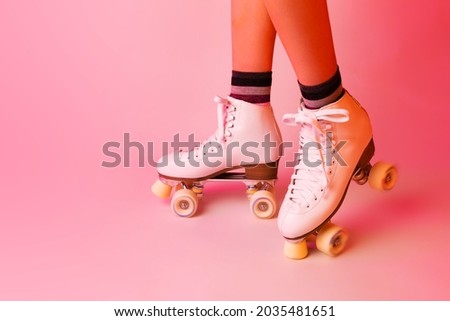 Sports equipment and recreation - classic white leather roller skates and girl’s legs. Pastel pink background. Layout with free copy (text) space.