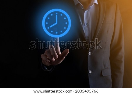 Businessman hand holds the icon of hours clock with arrow. Rapid execution of the work.Business time management and business time is money concepts.