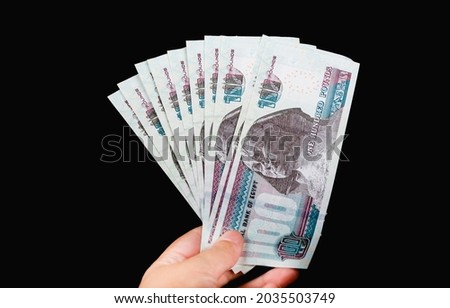 woman hand holding one thousand  Egyptian bounds ten hundreds isolated on black background Royalty-Free Stock Photo #2035503749