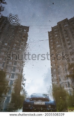 Reflection of a buildings and car in a puddle on the asphalt after a rain. Abstract photography.