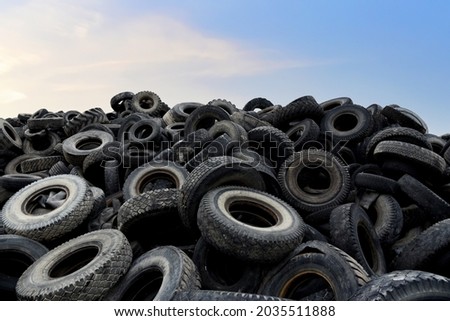 Landfill with old tires and tyres for recycling. Reuse of the waste rubber tyres. Disposal of waste tires. Worn out wheels for recycling. Tyre dump burning plant. Regenerated tire rubber produced. Royalty-Free Stock Photo #2035511888