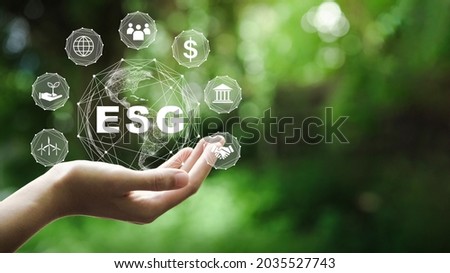 ESG icon concept in the hand for environmental, social, and governance in sustainable and ethical business on the Network connection on a green background. Royalty-Free Stock Photo #2035527743