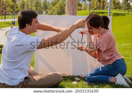 young couple in the park on the grass paint a picture with paints on a sunny summer day happiness and love in warm shades