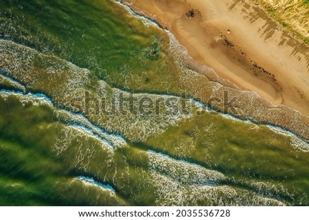 Aerial Top view shot of a sand beach being washed off by the waves of a sea, Baltic Sea side