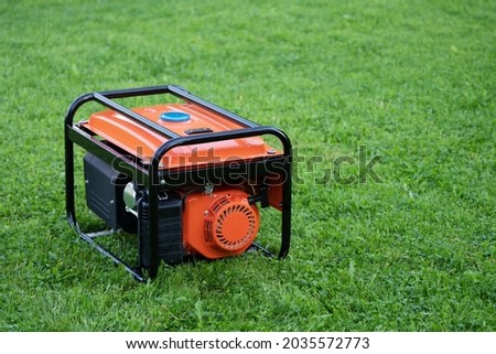 Portable electric generator on the green grass outdoors in summer Royalty-Free Stock Photo #2035572773
