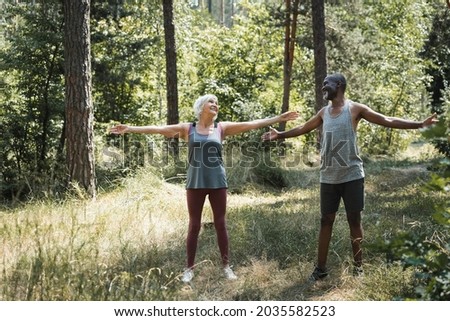 Smiling interracial couple training together in forest